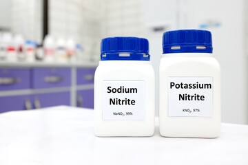 Selective focus of bottles of sodium nitrite and potassium nitrite chemical preservative. White...