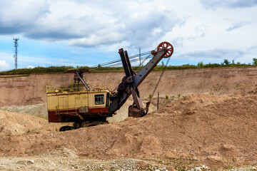 Quarry excavator in open pit mine. It can be seen working wall with earth layers on background
