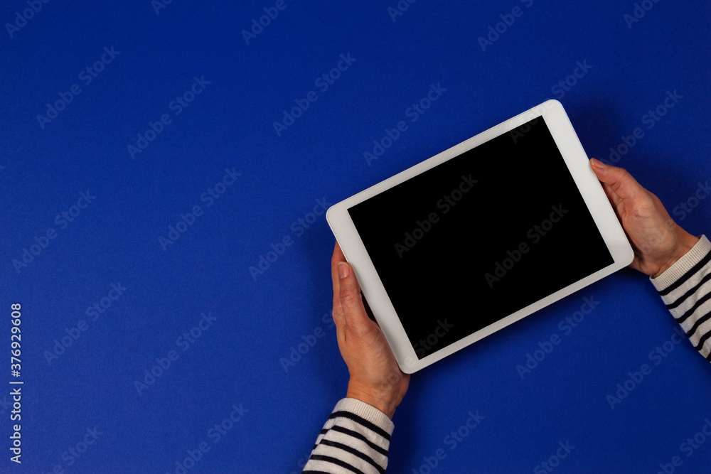 Wall mural female hands holding digital tablet computer on navy blue background. top view