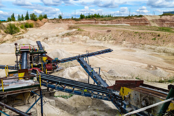 Stone crush machinery & its elements in open pit mine. Dumps of materials & loading area are on background