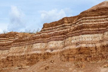 Earth wall in industrial quarry with open-pit mining. It can be seen very clearly underground...