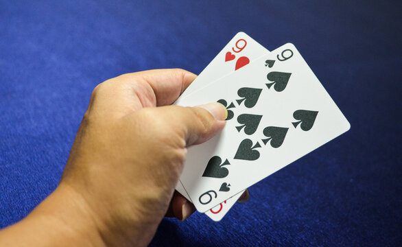 Hand Holding 9  Spade And 9 Heart Card On Baccarat Game. Playing Cards .