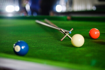 Man's hand and Cue arm playing snooker game or preparing aiming to shoot pool balls on a green...
