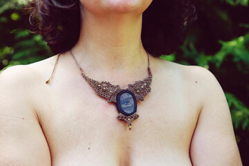 Female neckline wearing mineral gemstone necklace in macrame technique