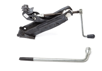 Kit for changing a wheel in case of a breakdown on the track - a wrench and a jack on a white isolated background in a photography studio, a spare tool is stored in the trunk of a car.