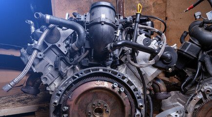 Obraz premium Powerful tuned gasoline engine with a turbocharger and charger in the engine compartment in disassembled form, removed from the car in a car workshop for auto parsing.