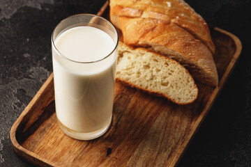 Glass of milk with sliced baguette on wooden board