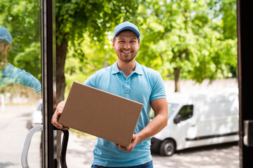  Smiling courier bring a package in the cardboard box to your house