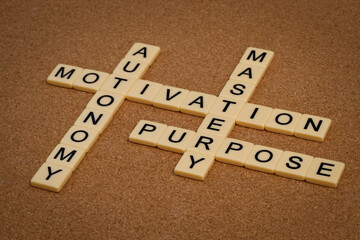 three elements of true motivation - mastery, autonomy, purpose - crossword with ivory letter blocks on cork board, personal development concept