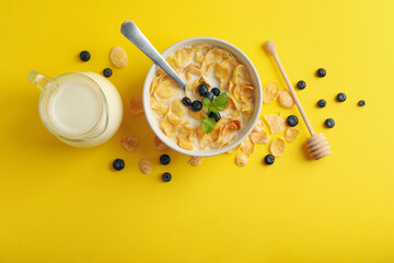 Milk, bowl of muesli and dipper on yellow background