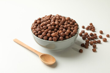 Spoon and bowl with corn balls on white background