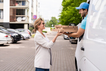 Delivery man in a white van delivers pizza to a woman client