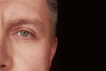 Closeup of adult man half face on dark background with copy space