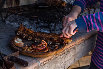 Man hands cutting meat on wooden dish.