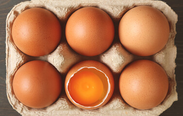 Pack of fresh organic eggs with an opened shell one in the carton box