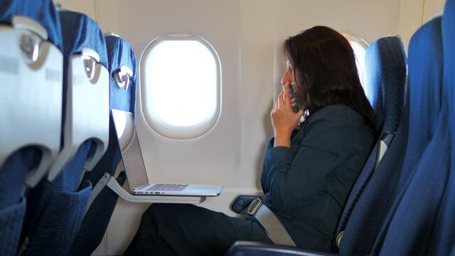 Asian woman feeling sick, get cough inside air plane while working on her laptop.