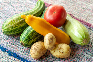 rural still life with a crop of vegetables on a woven carpet