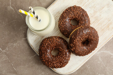 Jar of milk and tasty donuts on gray table