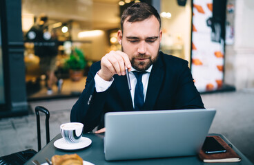 Serious businessman using laptop in cafe