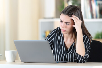 Fototapeta premium Worried woman checking laptop at home