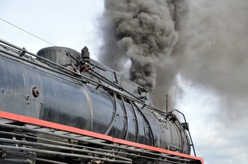 closeup view old steam locomotive train boiler with black grey smoke. Red line