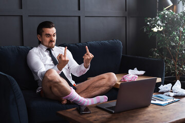 Angry businessman without pants showing rude gesture into the laptop's camera