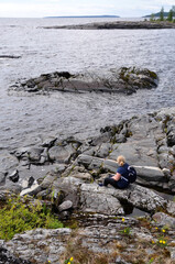 Young woman girl sitting on Rocky shore. Ladoga lake Skerry Russian Karelia