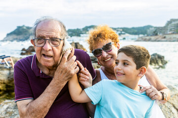 Grandparents and grandson playing with a shell on the beach