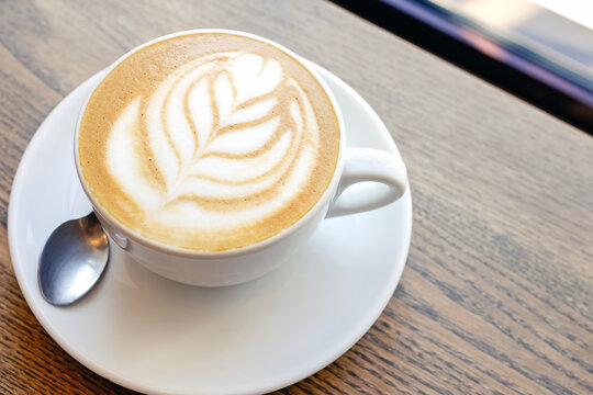 Close-up of hot cappuccino coffee dressing with leave shape of latte art
