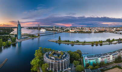 Fototapeta premium Riga city panorama with colorful sunset in the sky. Modern architecture meets old town. Picturesque view over riverside. 