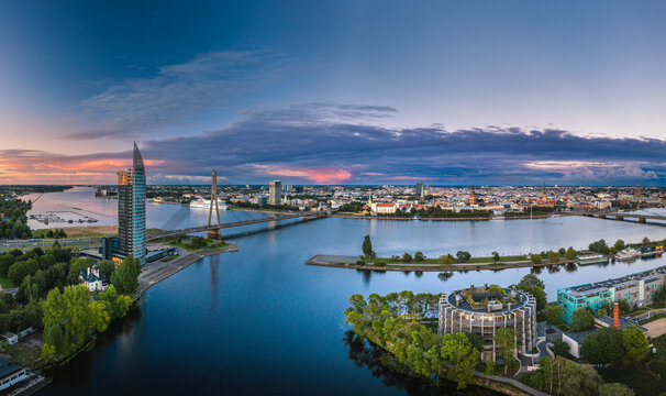 Riga city panorama with colorful sunset in the sky. Modern architecture meets old town. Picturesque view over riverside. 