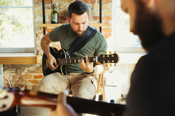 Inspiration. Musician band jamming together in art workplace with instruments. Caucasian men and...