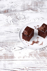 Piece of chocolate cake topped with ganache on the white table. Copy space