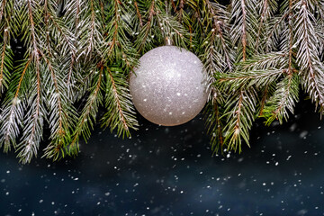 Silver Christmas ball on a snowy Christmas tree during a snowfall