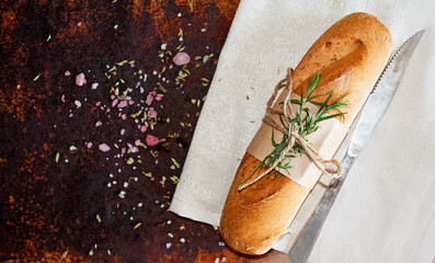 Fresh bread with tarragon on a rusty metal background, top view, copy space. Mini baguette bread...