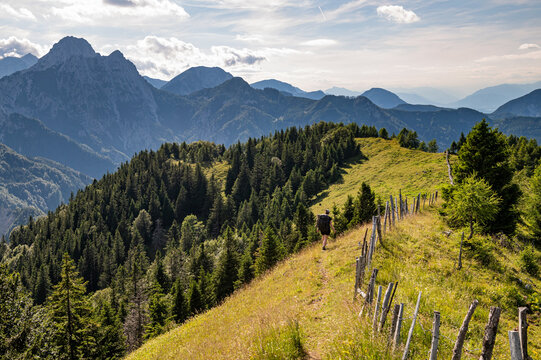 Young woman summer hiker backpack climbing steep slopes, panoramic mountains with valleys around. Female trekker in challenging terrain in Karavanke mountains, Slovenia Karawanken, Carinthia, Austria