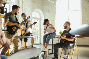 Inspiration. Musician band jamming together in art workplace with instruments. Caucasian men and women, musicians, playing and singing together. Concept of music, hobby, emotions, art occupation.