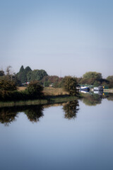 Fototapeta na wymiar pleasure boats on the canal, calm day with clear reflection on the water, trees and blue sky