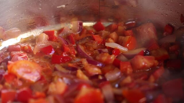 Vegetables are stewed in a stewpan on the fire, from which steam comes out. Close up