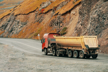 Truck carrying bulk materials moves along a road on the mountains highway