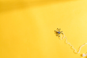 Halloween decoration spider with web on a yellow background.