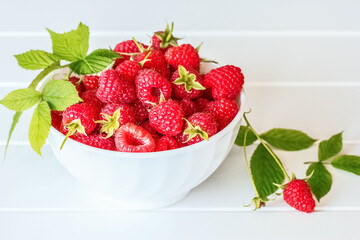 ripe raspberries in a white bowl on a white background. raspberries in a bowl close-up. background with raspberry macro.
