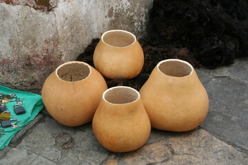 4 duże naczynia z tykw stojące na chodniku przy zniszczonym murze na bazarze w Meksyku obok...