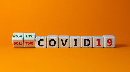 Test result of a Corona test. Turned a cube and changed the expression 'positive COVID19' to 'negative COVID19'. Beautiful orange background. Medical concept. Copy space.