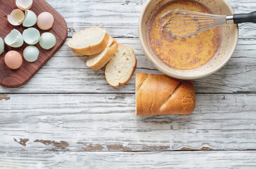 Fototapeta premium Bowl of French Toast mix with bread and eggshells nearby shot from top view, flatlay position with room for text.