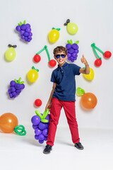 Fototapeta na wymiar stylish fashionable boy in sunglasses stands in background with fruit balls