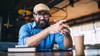Bearded middle aged man in eyeglasses sitting in cafe