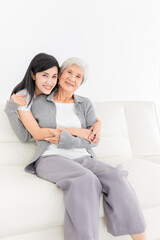 young Asian female hug old female in home, they feeling happy and smile, they sitting on sofa, mother's day, happiness elderly in family time