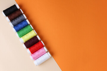 Accessories for sewing. Colored spools of thread on a yellow-orange background.