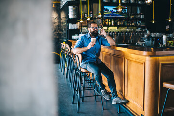 Handsome prosperous mature man in casual wear enjoying free time and coffee break near bar, smiling happy hospitable caucasian mature male entrepreneur spending time at job in restaurant